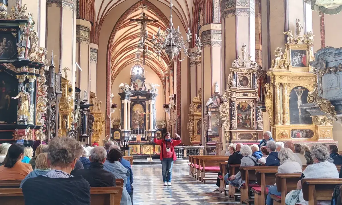 Wnętrze katedry we Fromborku, gdzie zwiedzający słuchają przewodniczki. Zamek Frombork zachwyca bogactwem zdobień.