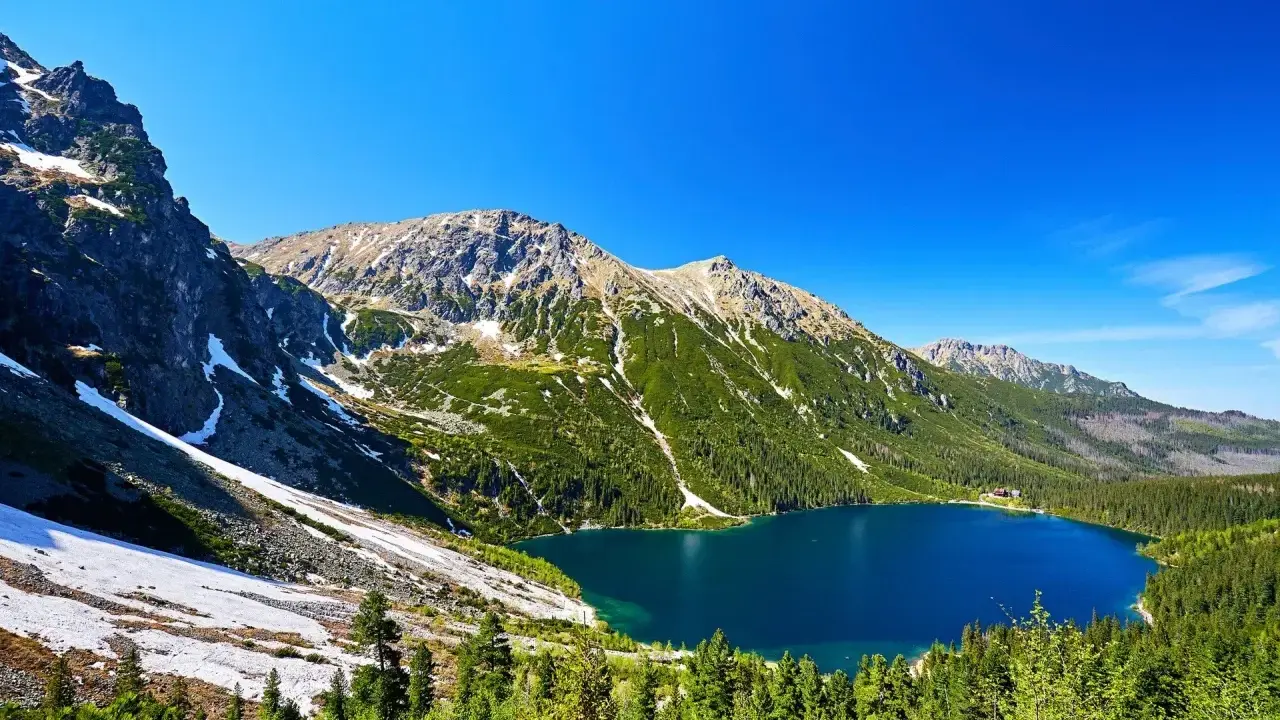 Malowniczy widok na Morskie Oko, idealne miejsce na górską trasę. Błękitne jezioro otoczone zielonymi lasami i skalistymi szczytami Tatr.