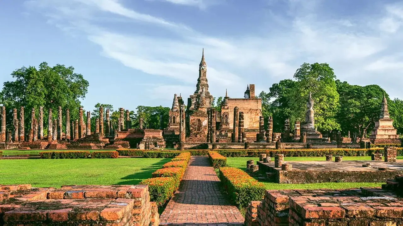 Ruiny świątyń w historycznym parku Sukhothai, wpisanym na listę 7 cudów świata UNESCO, z posągiem Buddy i wieżami.