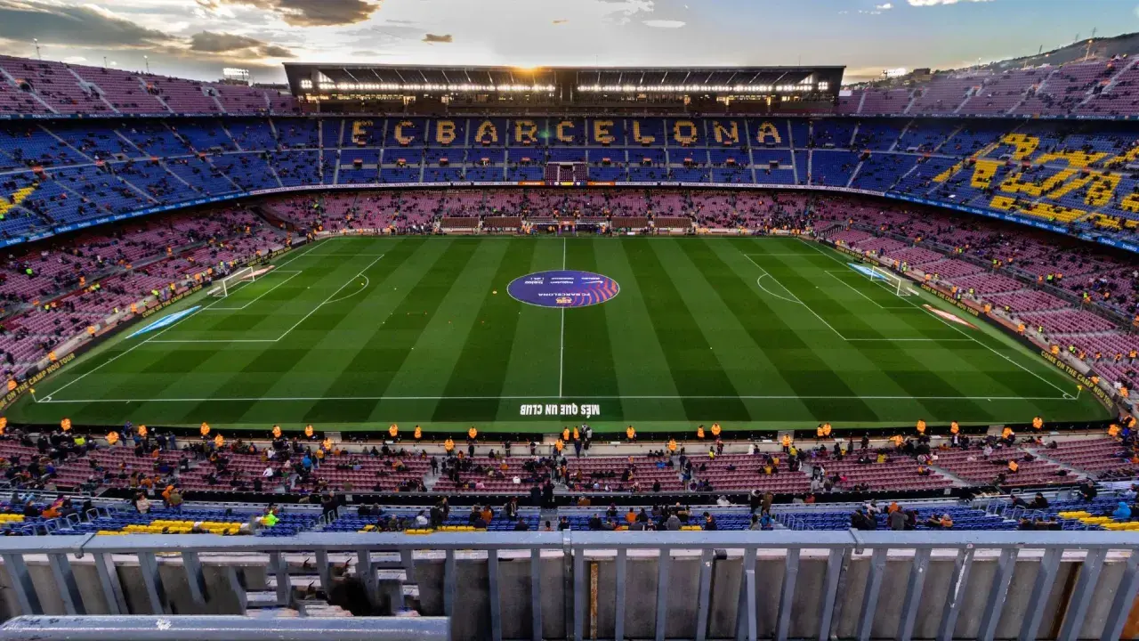 Widok na Camp Nou podczas zwiedzania. Piękny stadion FC Barcelona z murawą i trybunami wypełnionymi kibicami.