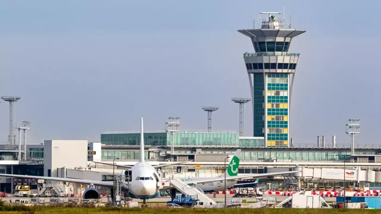 Wieża kontroli lotów i samoloty na jednym z lotnisk w Paryżu.