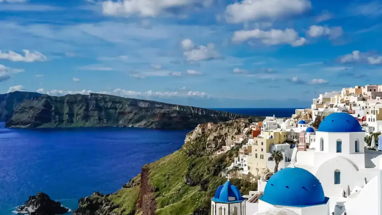 Santorini wakacje: białe domy z niebieskimi kopułami na klifie nad lazurowym morzem. Widok zapiera dech w piersiach.