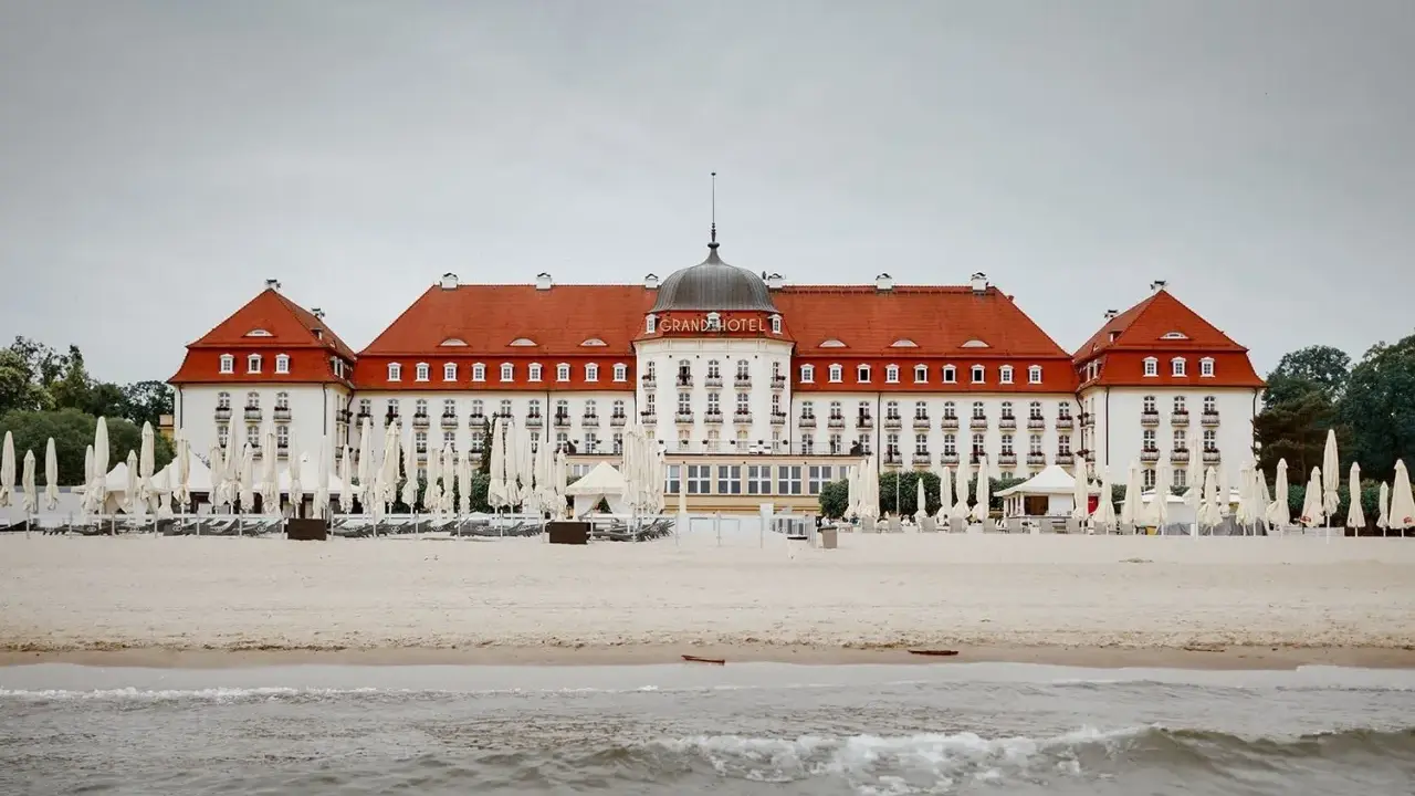 Majestatyczny Grand Hotel Sopot, z czerwoną dachem i białymi fasadami, stoi nad morzem. Jego historia jest równie imponująca jak widok.