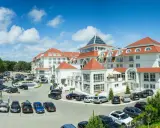 Elegancki hotel 5 gwiazdkowy nad morzem z parkingiem pełnym samochodów.