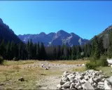 Widok na Tatry, być może Rysy 2499 czy 2503. Góry, las i kamienista dolina.