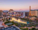 Las Vegas, miasto hazardu w USA, nocą. Widać fontanny, wieżę Eiffla i diabelski młyn.