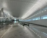 Nowoczesny, jasny korytarz lotniskowy z ruchomymi schodami w AUH Zayed International.