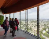 Grupa turystów podziwia panoramę miasta z tarasu widokowego najwyższego budynku we Wrocławiu.