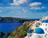 Santorini wakacje: białe domy z niebieskimi kopułami na klifie nad lazurowym morzem. Widok zapiera dech w piersiach.