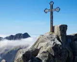 Krzyż na skalistym szczycie, najwyższy szczyt Karpat, góruje nad morzem chmur.