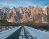 Droga przez ośnieżoną dolinę w kierunku majestatycznych gór Hunza.