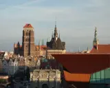 Gdańsk stare miasto z Bazyliką Mariacką i Ratuszem. Słońce oświetla zabytkowe kamienice i nowoczesną architekturę.
