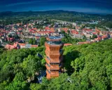 Nowoczesna wieża widokowa w otoczeniu zieleni, z panoramą miasta i Gór Wałbrzyskich w tle.