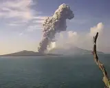 Potężna chmura dymu i popiołu wyrzuca w niebo wulkan Krakatau, tworząc dramatyczny widok nad spokojnym morzem.