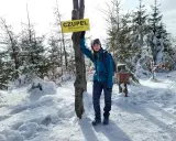 Dziewczyna na szczycie **Czupel** (933 m n.p.m.) w zimowej scenerii, z tabliczką i skrzynką na pieczątkę.