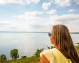 Kobieta w żółtej bluzce podziwia rozległe jezioro Balaton.