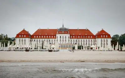 Majestatyczny Grand Hotel Sopot, z czerwoną dachem i białymi fasadami, stoi nad morzem. Jego historia jest równie imponująca jak widok.