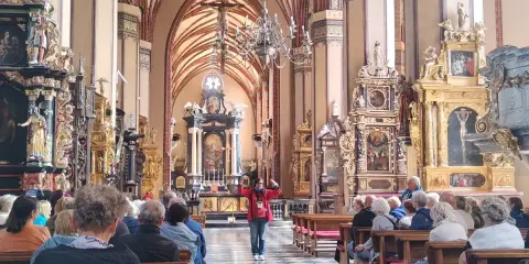Wnętrze katedry we Fromborku, gdzie zwiedzający słuchają przewodniczki. Zamek Frombork zachwyca bogactwem zdobień.
