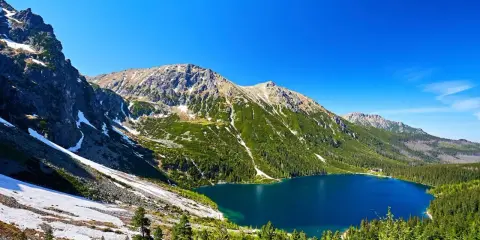 Malowniczy widok na Morskie Oko, idealne miejsce na górską trasę. Błękitne jezioro otoczone zielonymi lasami i skalistymi szczytami Tatr.