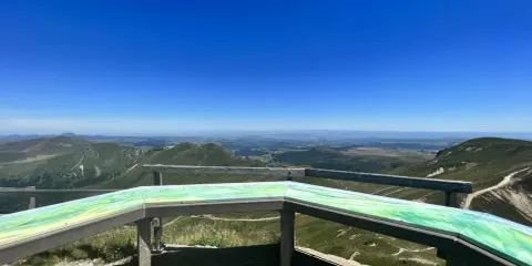 Widok na zielone wzgórza i doliny Masywu Centralnego z platformy widokowej.