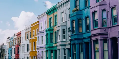 Kolorowe kamienice w Notting Hill w Londynie, tworzące tęczowy rząd pod błękitnym niebem.
