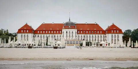 Majestatyczny Grand Hotel Sopot, z czerwoną dachem i białymi fasadami, stoi nad morzem. Jego historia jest równie imponująca jak widok.