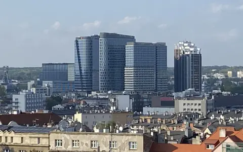 Nowoczesne wieżowce górują nad dachem kamienicy w największym mieście w Polsce.