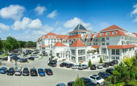 Elegancki hotel 5 gwiazdkowy nad morzem z parkingiem pełnym samochodów.