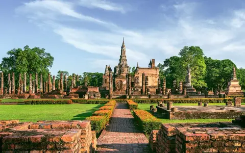 Ruiny świątyń w historycznym parku Sukhothai, wpisanym na listę 7 cudów świata UNESCO, z posągiem Buddy i wieżami.