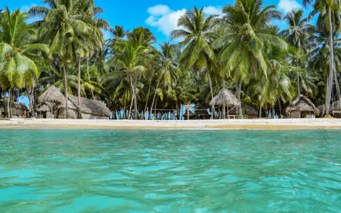 Rajska plaża San Blas z chatkami z liści palmowych i turkusową wodą.