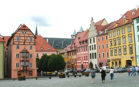 Kolorowe kamienice w **cheb** tworzą malowniczy rynek. Ludzie spacerują po brukowanym placu, podziwiając architekturę.