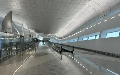 Nowoczesny, jasny korytarz lotniskowy z ruchomymi schodami w AUH Zayed International.