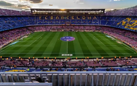 Widok na Camp Nou podczas zwiedzania. Piękny stadion FC Barcelona z murawą i trybunami wypełnionymi kibicami.
