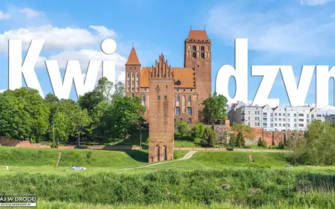 Zamek w Kwidzynie, imponująca budowla z cegły, góruje nad zielonym krajobrazem.