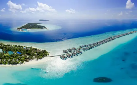 Rajskie wakacje na Malediwach, wyspiarskim państwie na Oceanie Indyjskim. Luksusowe bungalowy na wodzie i zielona wyspa z resortem.