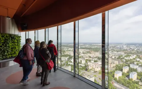 Grupa turystów podziwia panoramę miasta z tarasu widokowego najwyższego budynku we Wrocławiu.