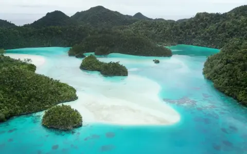 Rajskie krajobrazy Raja Ampat: turkusowe laguny, piaszczyste ławice i bujna zieleń tropikalnych wysp.