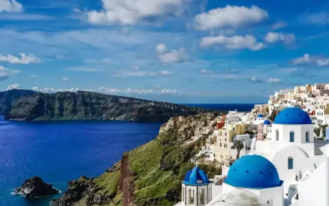 Santorini wakacje: białe domy z niebieskimi kopułami na klifie nad lazurowym morzem. Widok zapiera dech w piersiach.