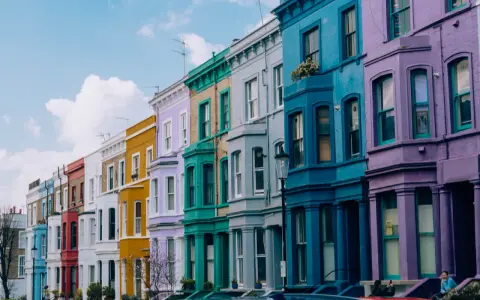 Kolorowe kamienice w Notting Hill w Londynie, tworzące tęczowy rząd pod błękitnym niebem.