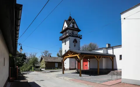 Wieża zegarowa i drewniany domek w słoneczny dzień.
