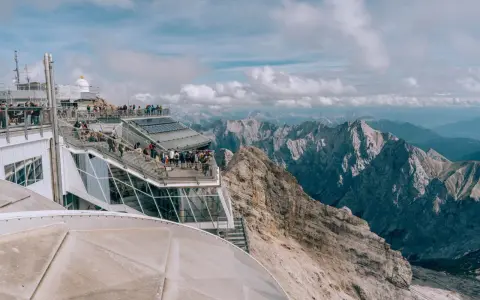 Tłum turystów na tarasie widokowym najwyższego szczytu Niemiec, Zugspitze, podziwia alpejskie krajobrazy.
