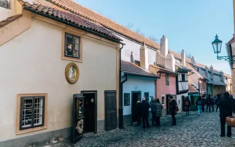 Urokliwa, brukowana złota uliczka w Pradze, z kolorowymi domkami i turystami spacerującymi pośród nich.