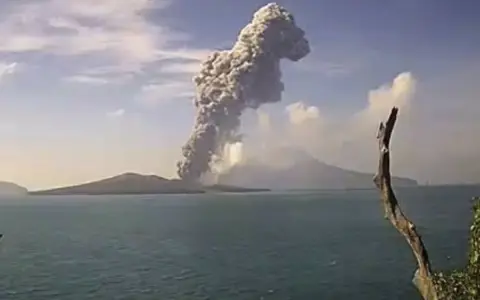 Potężna chmura dymu i popiołu wyrzuca w niebo wulkan Krakatau, tworząc dramatyczny widok nad spokojnym morzem.