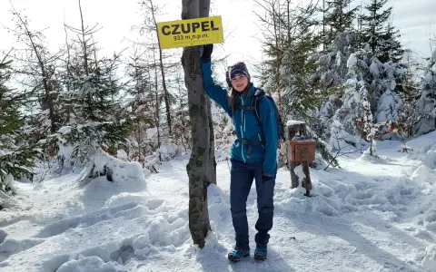 Dziewczyna na szczycie **Czupel** (933 m n.p.m.) w zimowej scenerii, z tabliczką i skrzynką na pieczątkę.