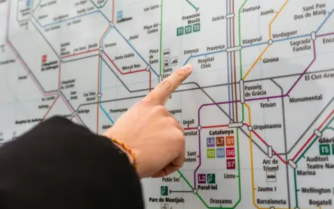 Palec na mapie metra w Barcelonie, wskazujący drogę do Hospital Clínic. Planujesz podróż z lotniska Barcelona?