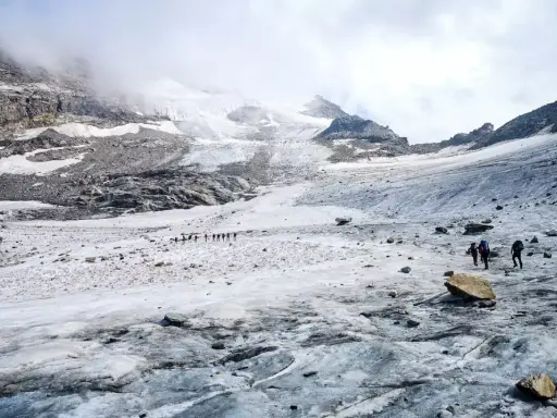Grupa turystów wędruje po lodowcu w kierunku majestatycznego masywu Monte Rosa.