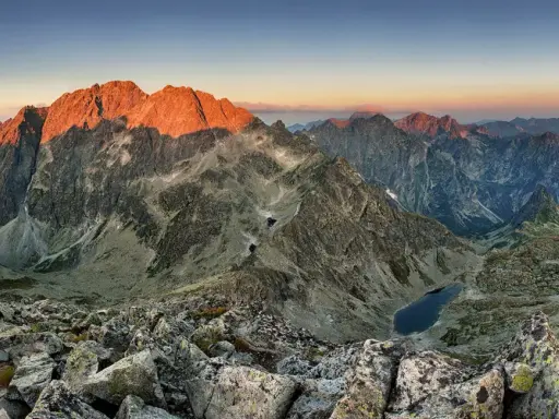 Zachód słońca nad najwyższym szczytem w Tatrach, oświetlającym skaliste zbocza i górskie jeziora.