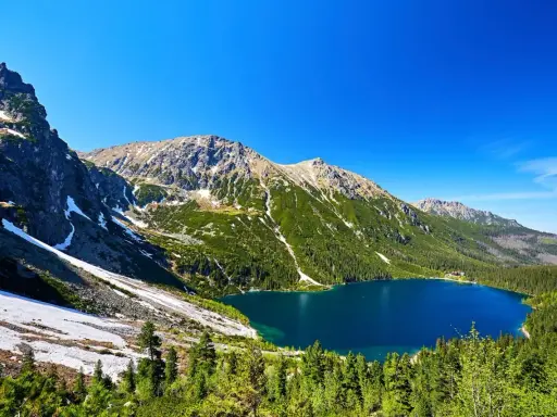 Malowniczy widok na Morskie Oko, idealne miejsce na górską trasę. Błękitne jezioro otoczone zielonymi lasami i skalistymi szczytami Tatr.
