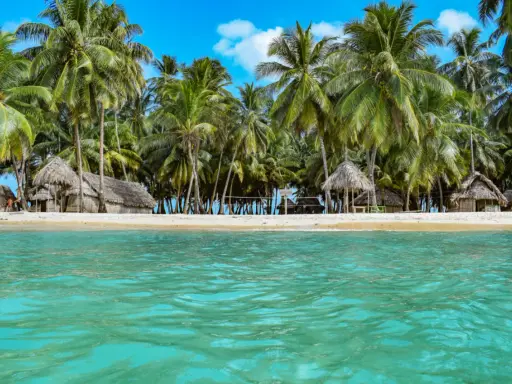 Rajska plaża San Blas z chatkami z liści palmowych i turkusową wodą.