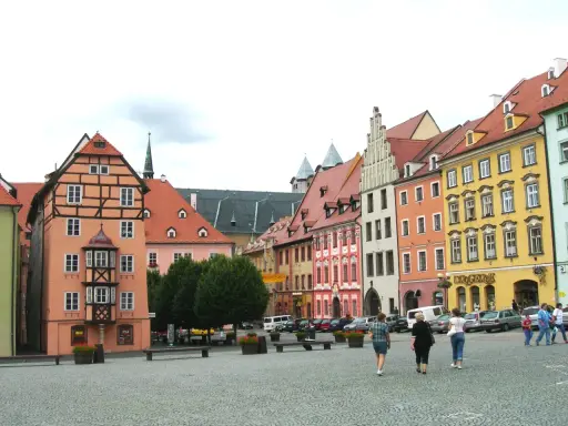 Kolorowe kamienice w **cheb** tworzą malowniczy rynek. Ludzie spacerują po brukowanym placu, podziwiając architekturę.